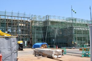 足場で覆われた建物と資材が並ぶ建設現場の様子