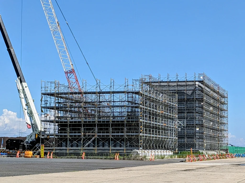 クレーンと足場が組まれた大型建築工事の現場全景