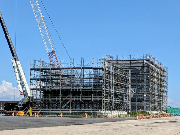 クレーンと足場が組まれた大型建築工事の現場全景