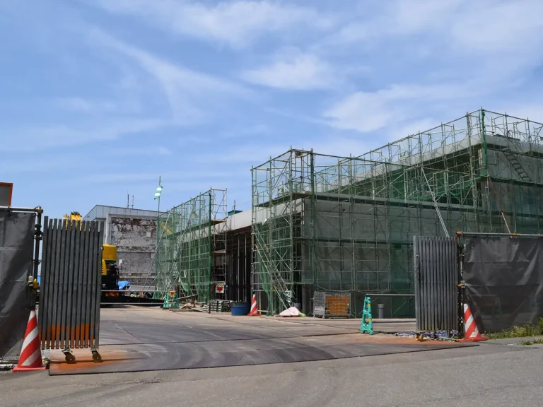 工事中の施設入口と、足場に囲まれた建物の外観