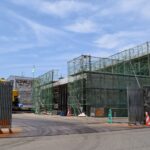 工事中の施設入口と、足場に囲まれた建物の外観